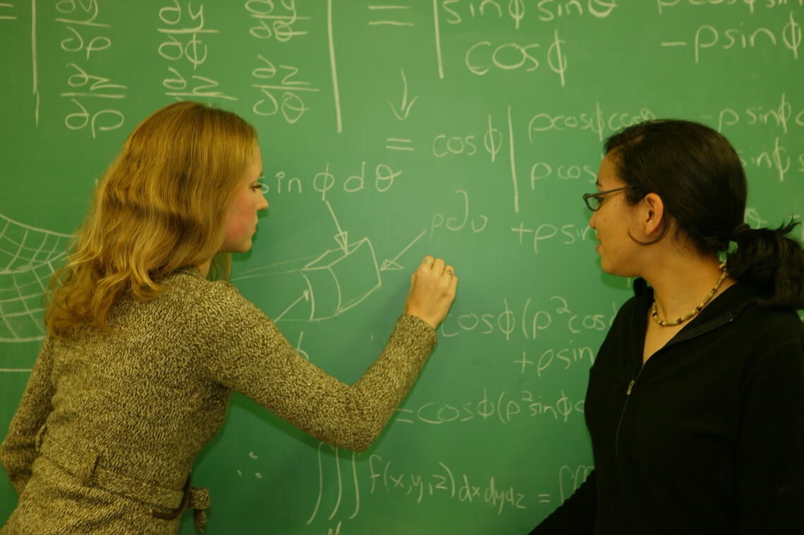 Students solving a math problem on a blackboard